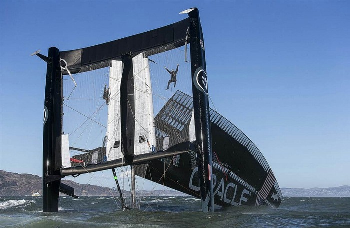 Thành viên đội đua thuyền Oracle (Mỹ) bám trụ trên chiếc thuyền của họ trong lúc thuyền từ từ đắm tại vịnh San Francisco.